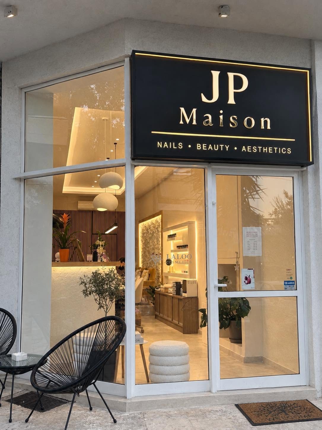 Η είσοδος του Maison JP με τη φωτισμένη μαύρη ταμπέλα και το ζεστό εσωτερικό